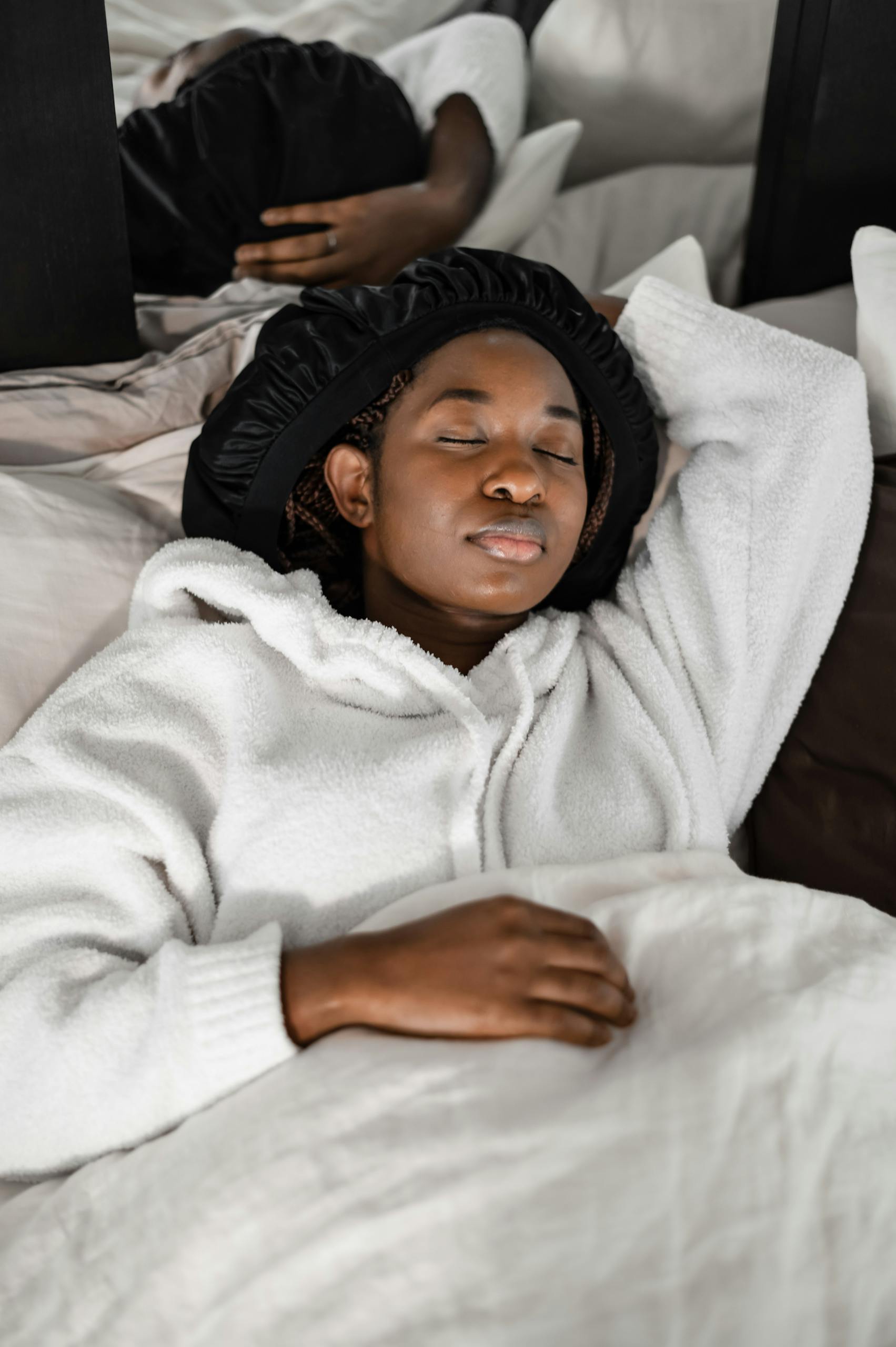 A serene African American woman resting peacefully on a comfortable bed, enhancing relaxation.