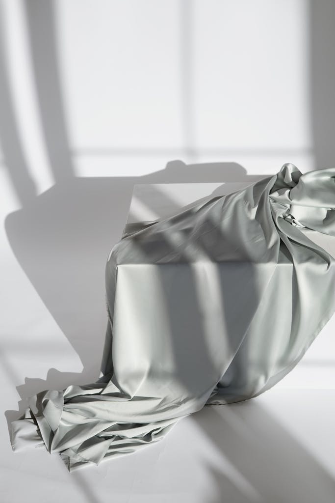 FAQs for Muriersilk Silk fabric draped gracefully over a table, casting intricate shadows in soft natural light.